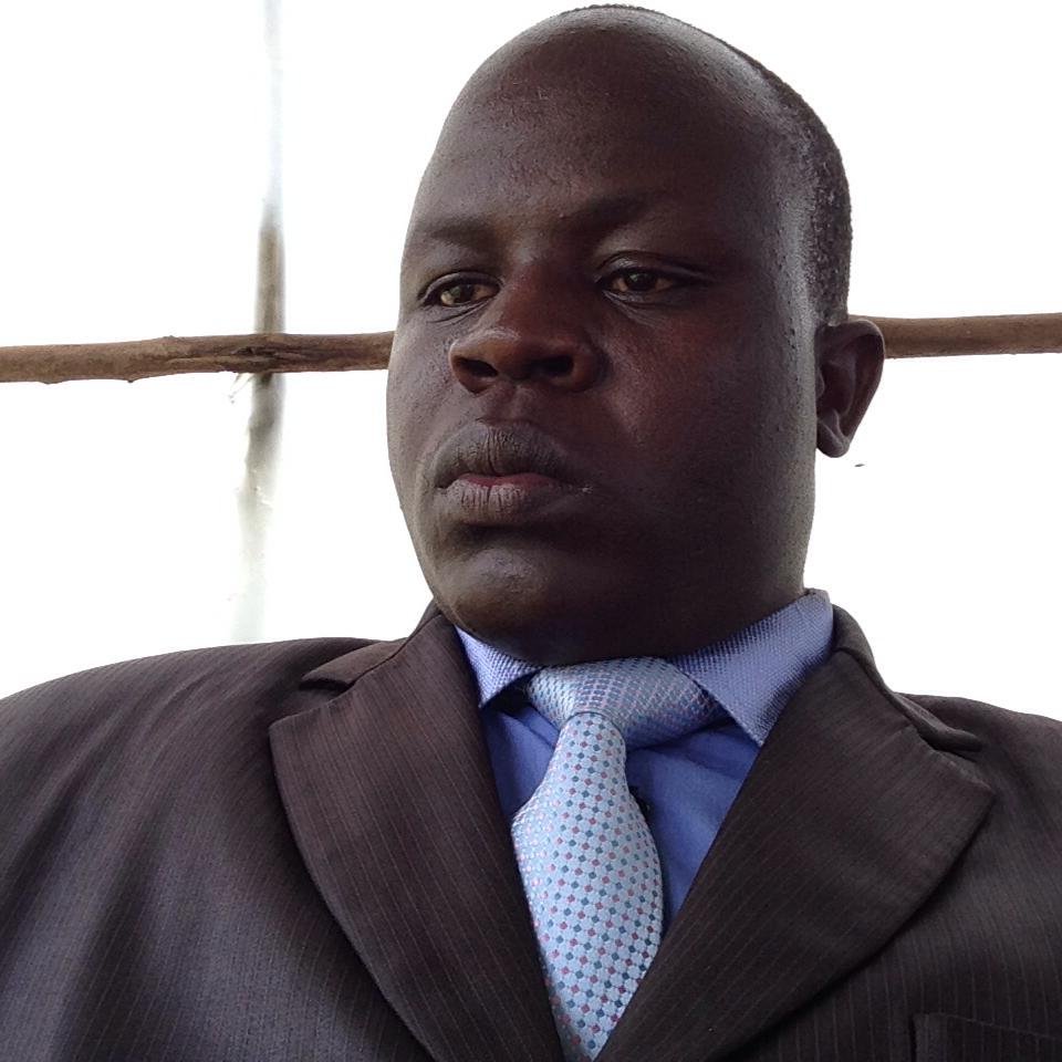 A man in a suit and tie looking serious, set against a light background.