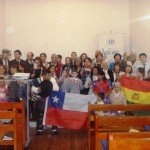 Group at church event holding Chilean and Bolivian flags, celebrating multicultural gathering indoors.