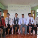 Group of six men sitting in front of a welcome sign at Asian Christian Theological Seminary.