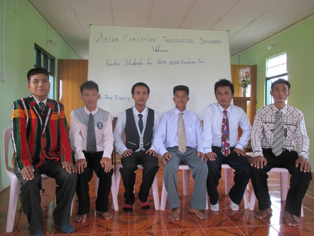 Group of six men sitting in front of a welcome sign at Asian Christian Theological Seminary.