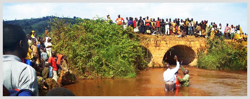 Crowd gathered on bridge, two people standing in river, vibrant community scene, Burundi celebration event.