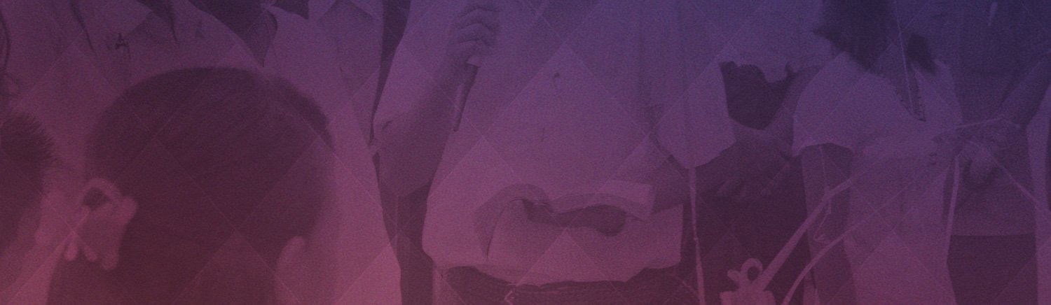 A speaker addresses a group at a meeting, holding a microphone and a book, with a purple hue overlay.