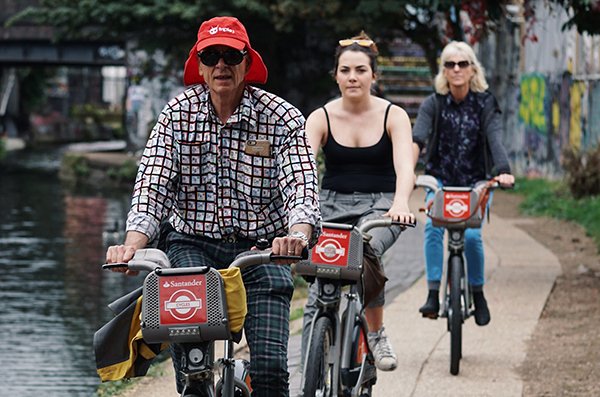 People riding bicycles along a canal path, enjoying an outdoor cycling experience.